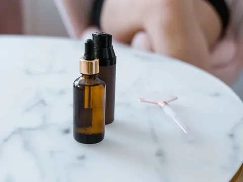 Serum bottles on a marble table with a person out of focus behind them.