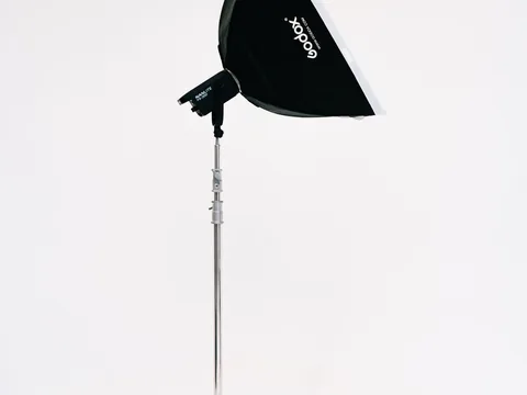 A softbox on a light stand set up against a plain studio wall.