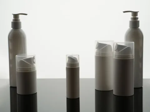 Pump bottles standing on a white surface with a clean reflection beneath them.